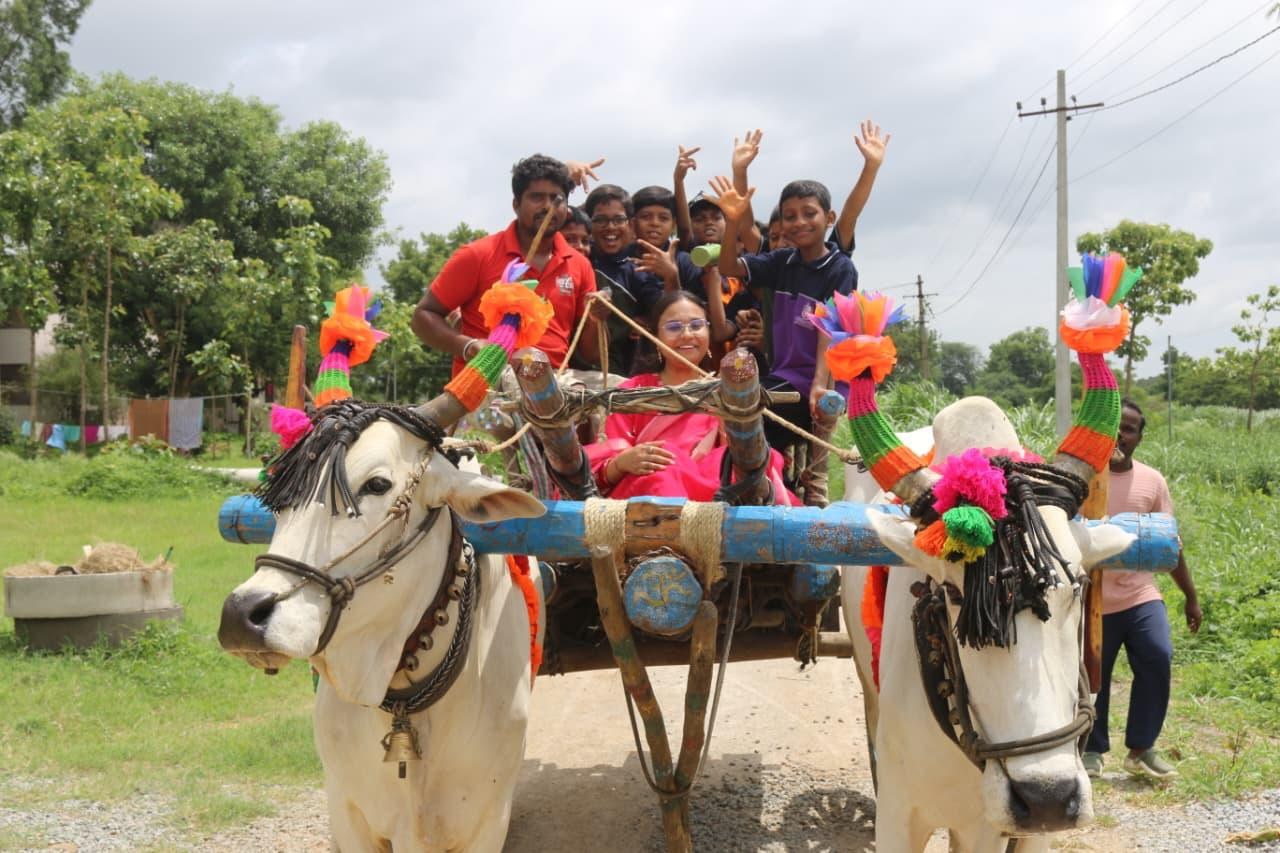 Children and teachers riding a decorated bullock cart