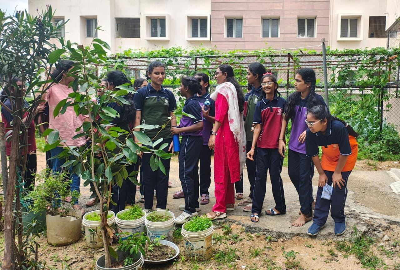 Students and a teacher working with potted plants outside a school building